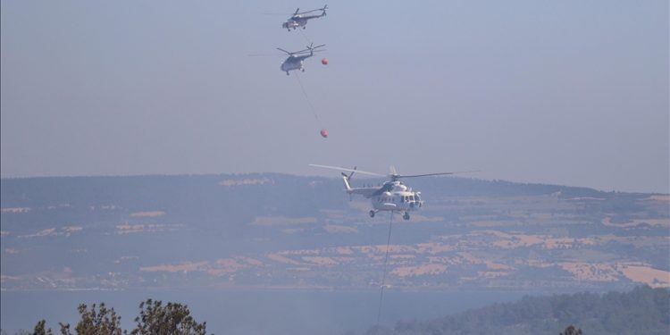 Firefighter helicopters drop water as teams conduct extinguishing works by land and air to control wildfires in Canakkale, Turkiye on July 17, 2023.
