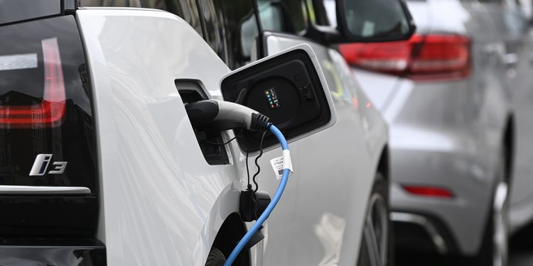 An electric car is charged at a roadside EV charge point.
