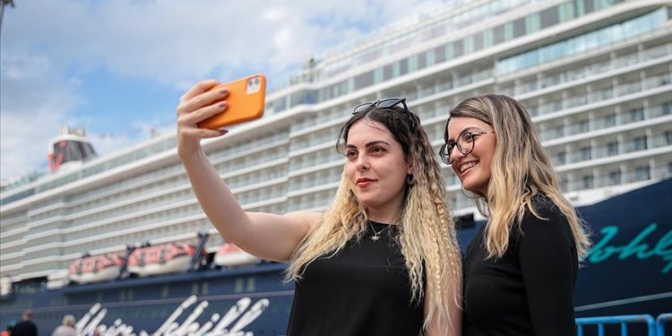 Two tourists take a selfie in front of a cruise ship.